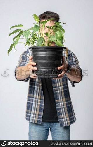 A man stood and held a plant pot in his house.