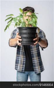 A man stood and held a plant pot in his house.
