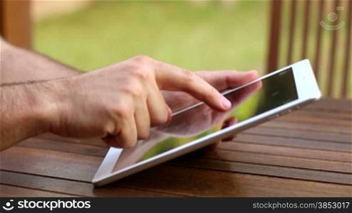 A man surfing the net with his iPad.Two hands touching the tablet screen and browsing.Leisure time touching iPad.