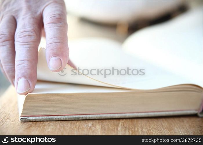 A man turns the pages of a large book.