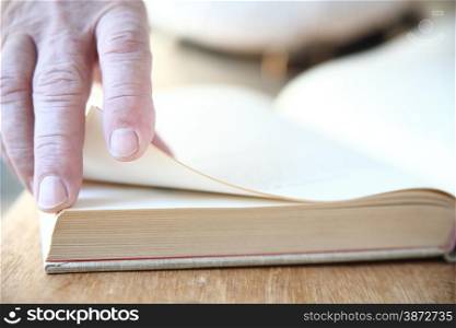A man turns the pages of a large book.