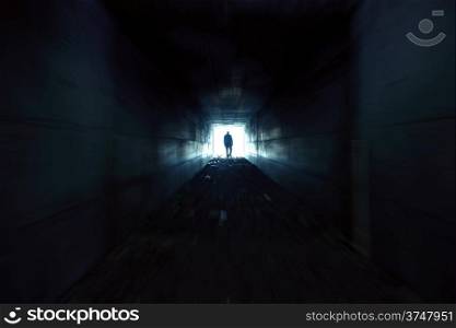 A man walking alone in the dark tunnel
