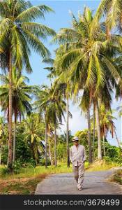 A man walking along the road in palm forest