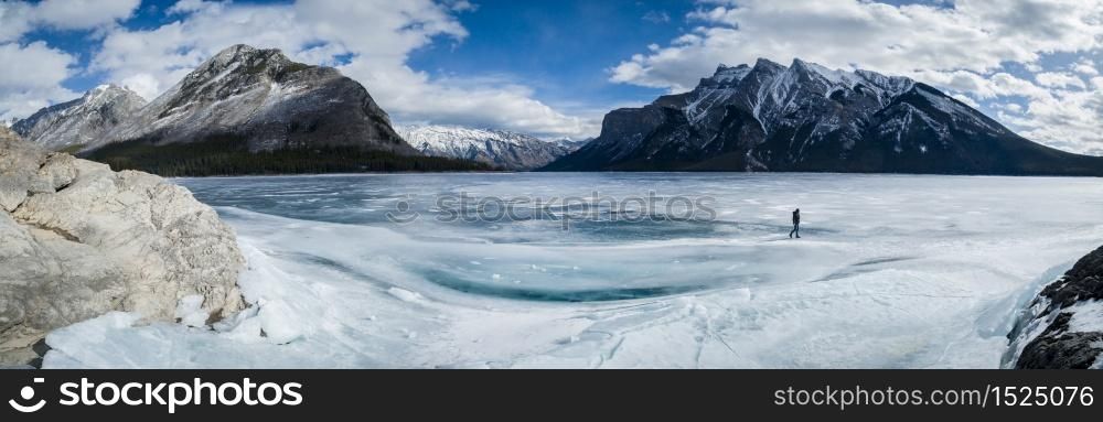A man walking on a frozen lake Minnewanka in Canadian Rockies