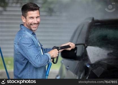 a man washes a car with a hose