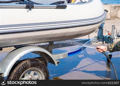 A man washes a rubber hose boat after going to sea. Drops of water scatter from the boat.