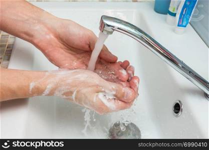 A man washes his hands from the thick suds