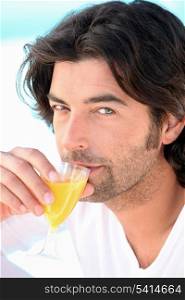 a man wearing a bathrobe and drinking orange juice