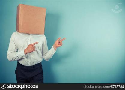 A man with a cardboard box on his head is pointing