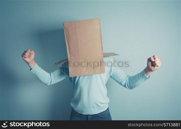 A man with a cardboard box on his heaqd is excited and is raising his arms
