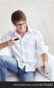 A man with a cup of coffee switch TV channels