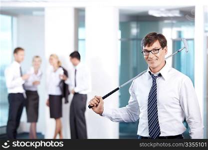 A man with a golf club against a background of office workers