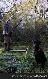 A man with a hunting with a black labrador