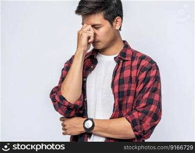 A man with a migraine headache holding her hand in her nose