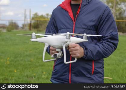 A man with a quadrocopter in his hands. A white drone is being prepared for the flight. Phantom. A man with a quadrocopter in his hands. A white drone is being prepared for the flight. Phantom.