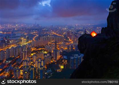 A man with tent standing on Suicide cliff in Hong Kong Downtown, China. Financial district and business centers in technology smart city in Asia. Skyscraper and high-rise buildings at night.