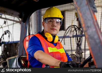 A man with yellow safety helmet and goggles driving a forklift or reach truck at the logistics warehouse store. Industrial, Mechanic, Engineering Concept.