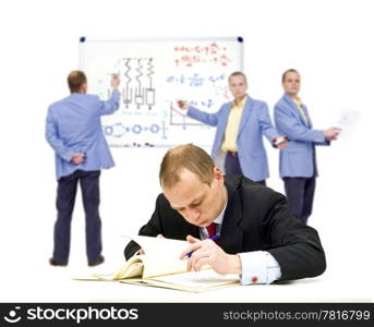A manager, trying to understand some very complex theories, oblivious of the people in the background trying to explain it to him