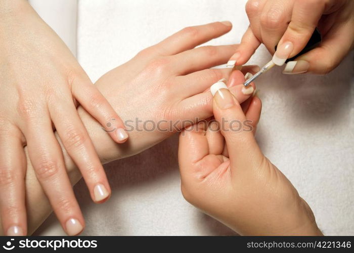 A manicurist applying nail polish during a manicure.