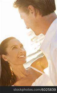 A married couple, bride and groom, together in sunset sunshine on a beautiful tropical beach
