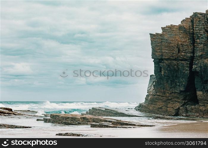 A massive cliff near the wild sea in the beach of the cathedrals in spain with copy space
