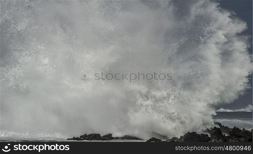 A massive wave explodes and disintergrates as it brakes on the shoreline