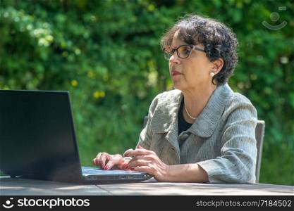 a mature brunette using laptop in the garden