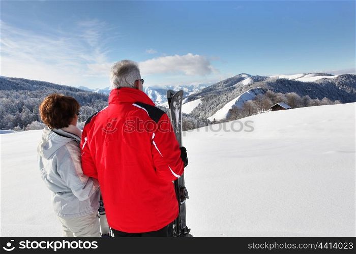 a mature couple in front of a beautiful snowy landscape