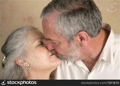 A mature couple sharing a passionate kiss. Focus on him.