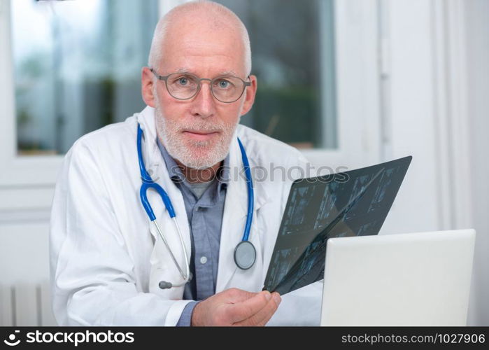 a mature Doctor looking at an x-ray in an office