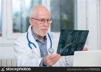 a mature Doctor looking at an x-ray in an office