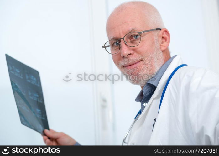 a mature Doctor looking at an x-ray in an office