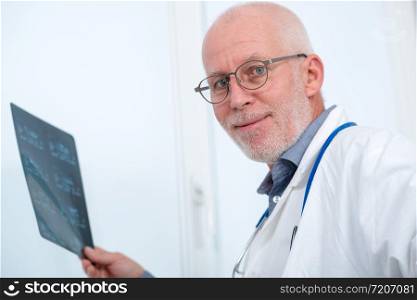 a mature Doctor looking at an x-ray in an office