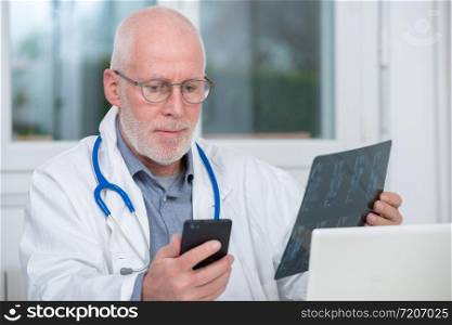 a mature doctor looking at x-ray picture and using telephone