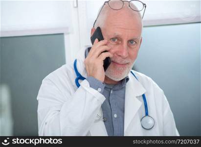 a mature doctor on phone at his office