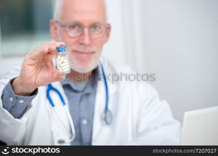 a mature doctor with pill in hospital