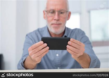 a mature handsome man using smartphone at home