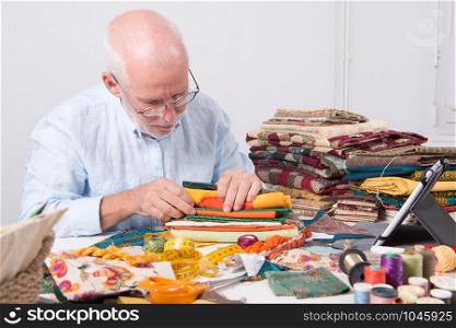 a mature man tailor choosing some fabric