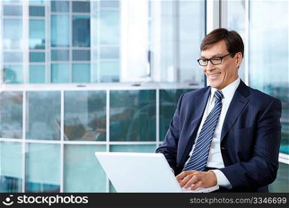 A mature man with laptop in the office