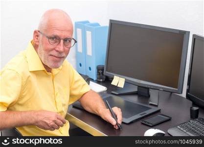 a mature man working with graphics tablet in his office
