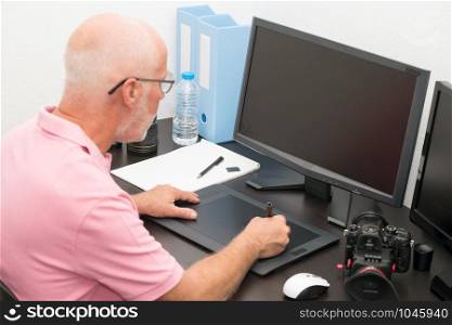 a mature man working with graphics tablet in his office