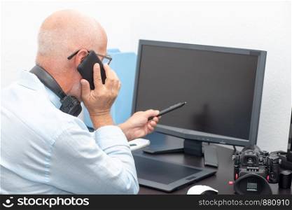 a mature photographer in his office phone