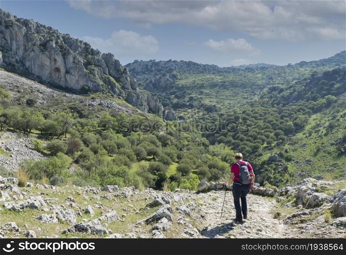 A mature woman busy on a mountain walk with backpack in the spanish part called andalusia near cordoba. woman busy with track in andalusia