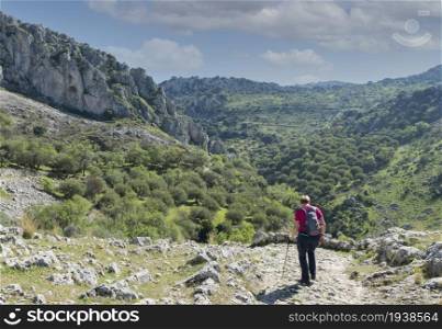 A mature woman busy on a mountain walk with backpack in the spanish part called andalusia near cordoba. woman busy with track in andalusia