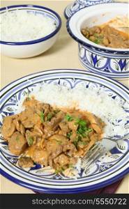 A meal of beef stroganoff with white rice and a fork on a table, vertical orientation