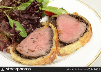 A meal of beef wellington, or boeuf en crout, served with a salad of lollo rosso lettuce, cherry tomatos and baby spinach leaves.