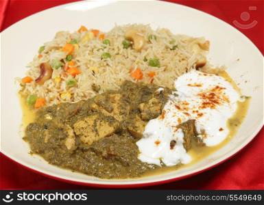 A meal of chicken saag (spinach) curry served with yoghurt and chilli, and a vegetable pulau rice