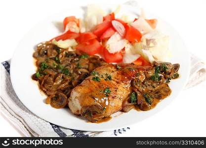 A meal of chicken topped with a creamy mushroom sauce and served with a salad. Plate on a cloth, over white.