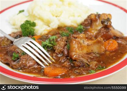 A meal of English oxtail stew, served with mashed potato and garnished with parsley