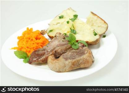 a meal of lamb loin chops with a baked potato and grated braised garlic carrots garnished with chopped parsley and sprigs of mint